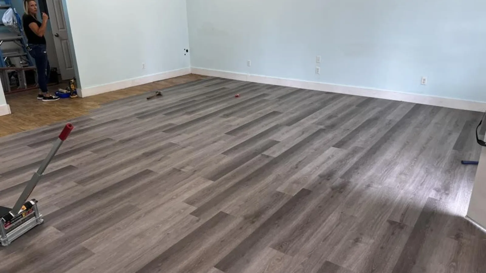Gray luxury vinyl plank flooring being installed across a Savannah living room by H.E. Douglas