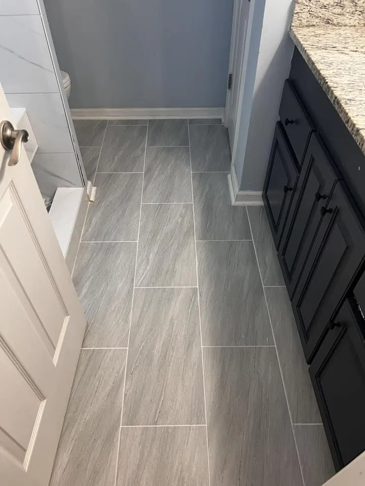 Remodeled bathroom with marble-look tile and a dark vanity by H.E. Douglas in Savannah