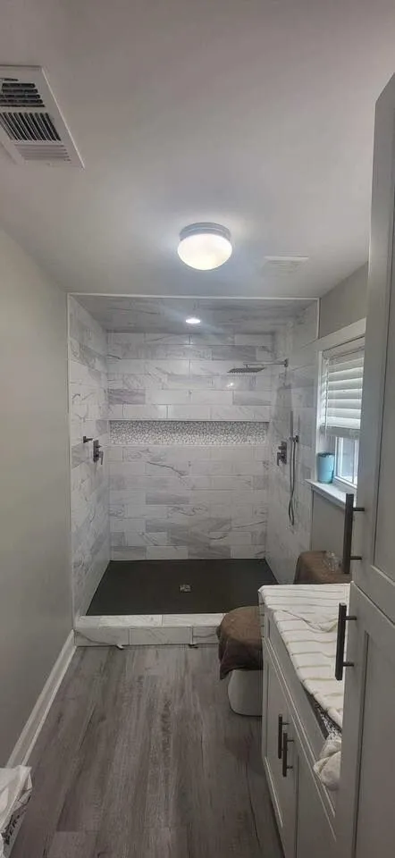 Compact Savannah bathroom with wood-look luxury vinyl plank flooring leading to a tiled shower