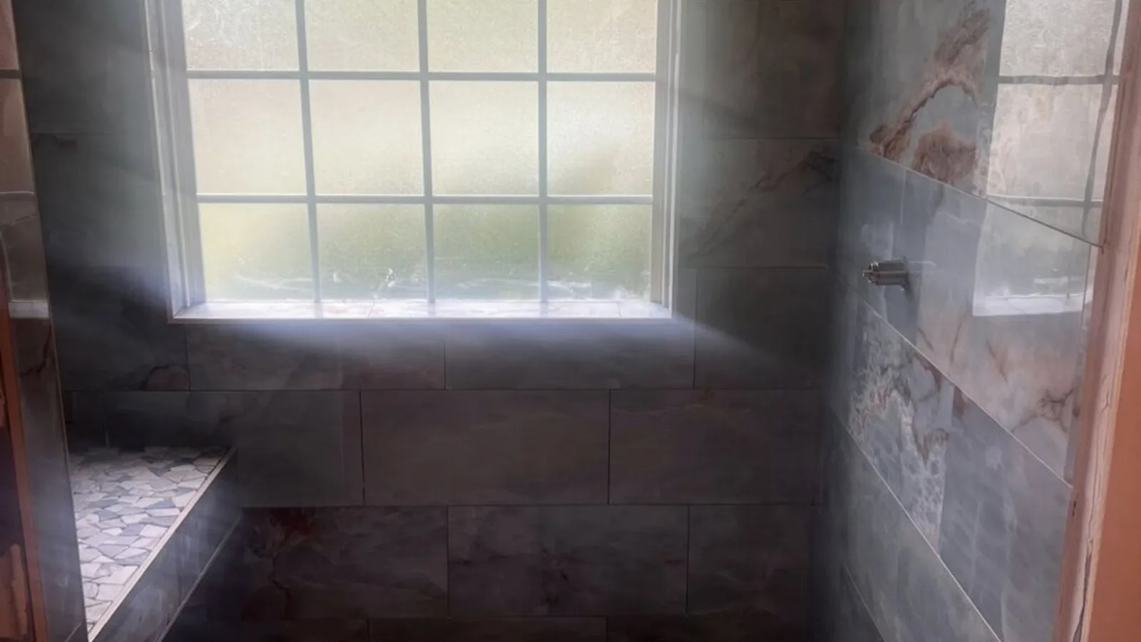 Compact white tiled bathroom shower with a bench and window in a Savannah home by H.E. Douglas