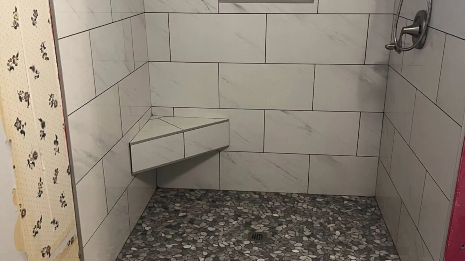 Finished white marble-look custom tile walk-in shower with bench and pebble floor built by H.E. Douglas in Savannah