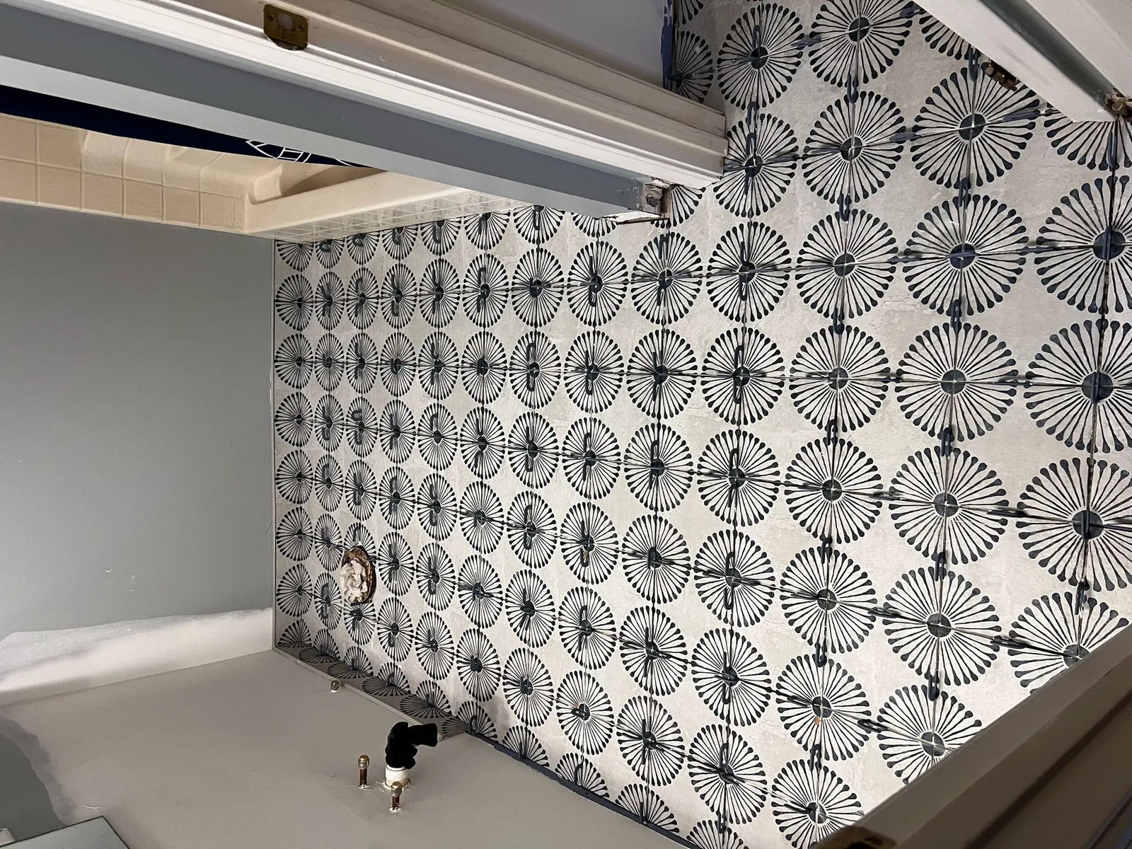 Bathroom tub surround tiled in a navy-and-white patterned floral cement-look tile