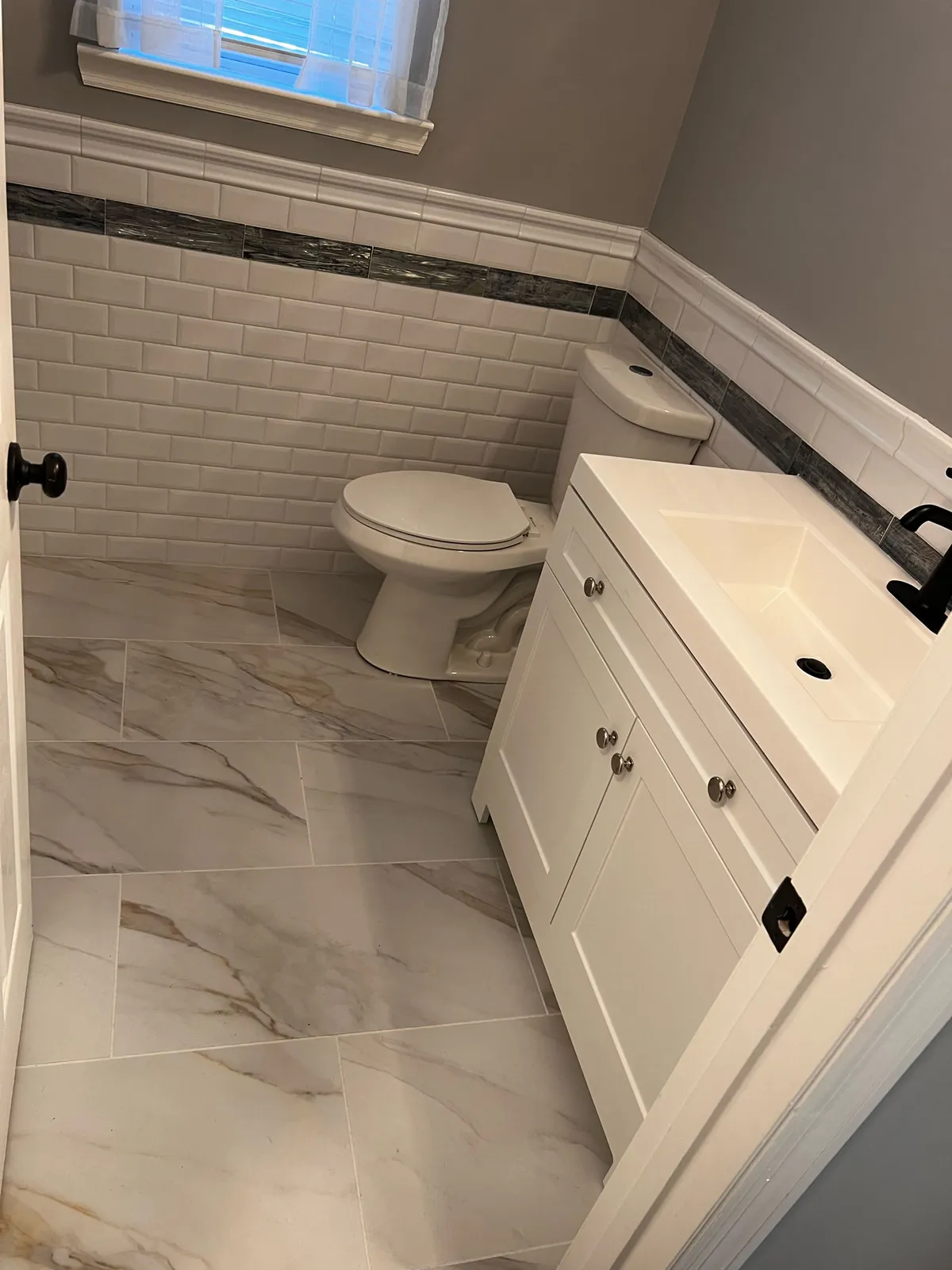 Finished bathroom with marble-look floor tile, white subway shower walls, and a shaker vanity