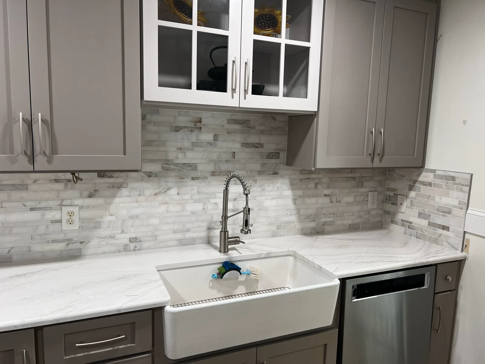 Gray shaker kitchen with quartz counters, marble linear-tile backsplash, and a white farmhouse sink