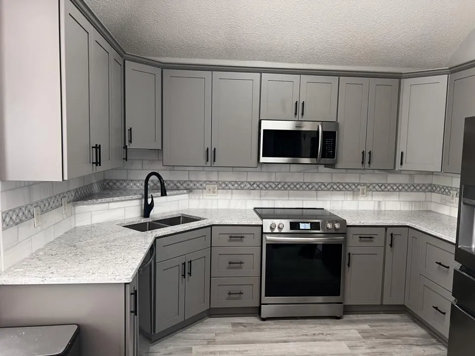Gray shaker cabinets refinished with black hardware and stone counters