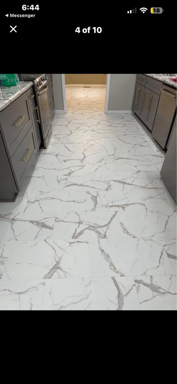 White marble-look porcelain tile floor laid through a gray kitchen