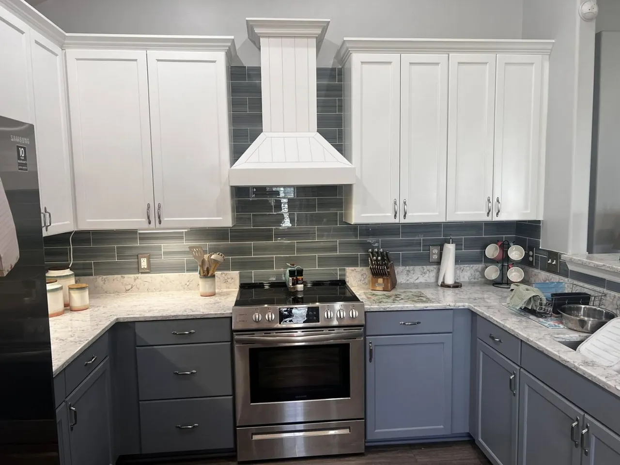 Two-tone white and blue refinished kitchen cabinets with a shiplap range hood