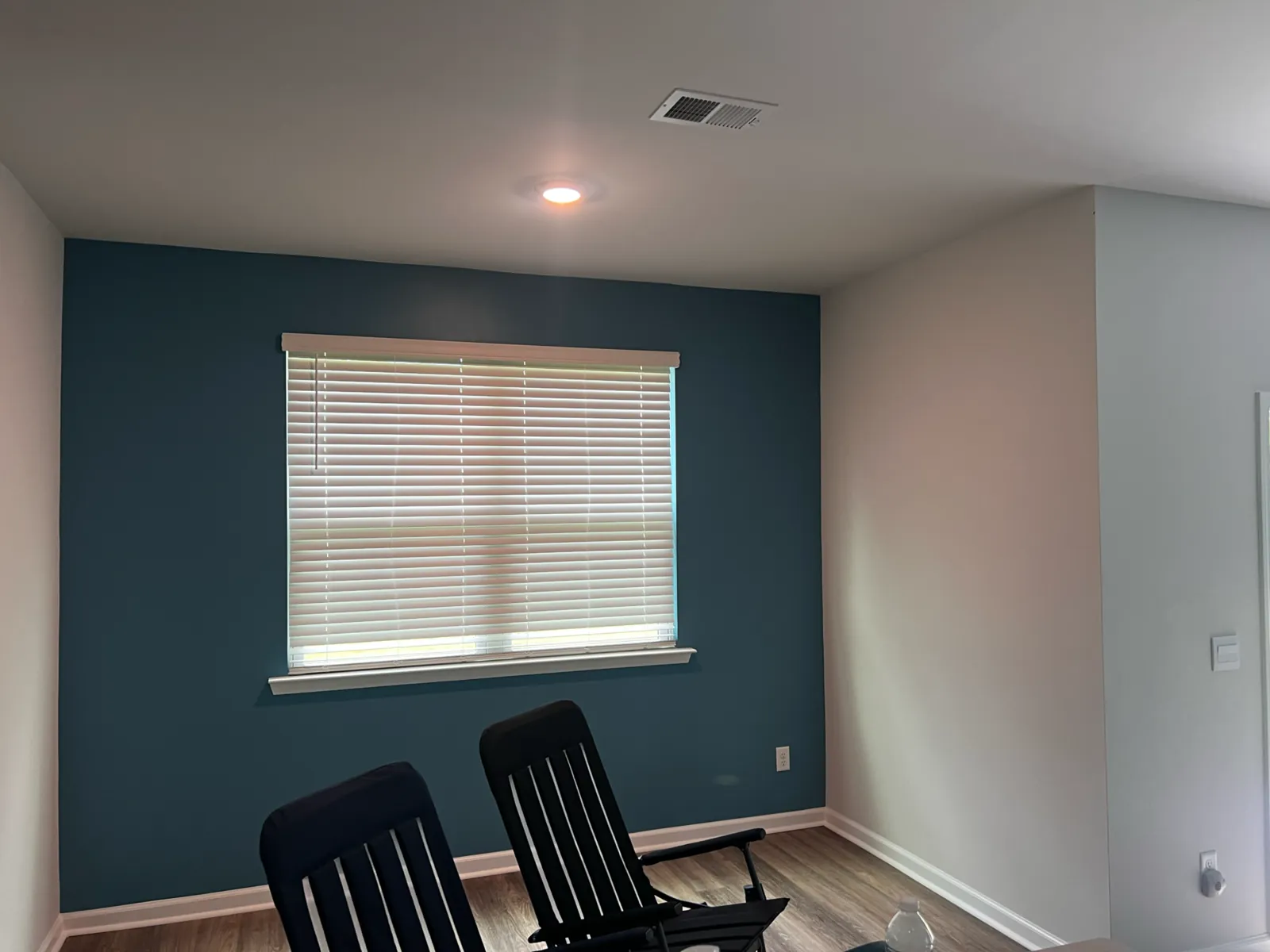 Sitting room with a deep teal-blue accent wall, white walls, and wood-look flooring