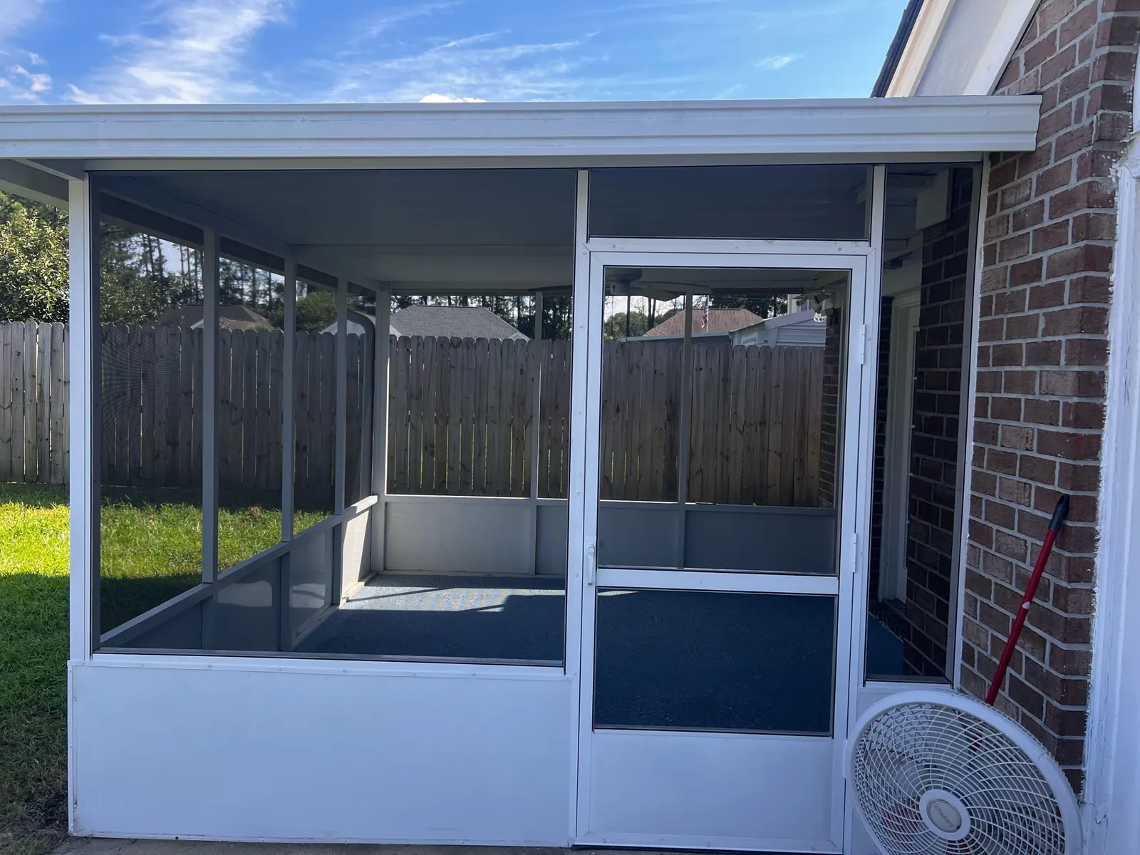 Screened porch with a hinged screen door and low kickplate on a brick house
