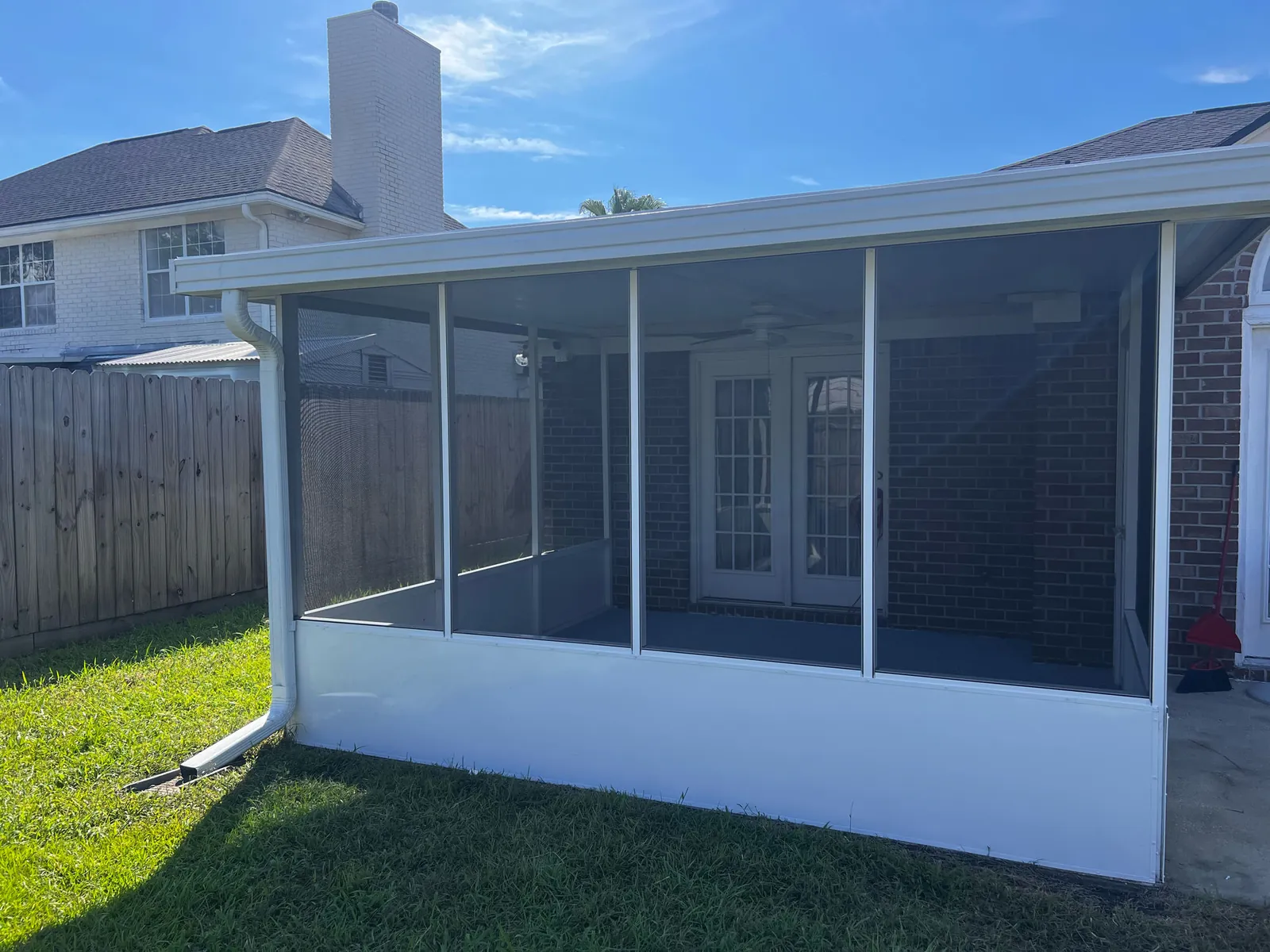 White aluminum screened porch enclosure added to the back of a brick home