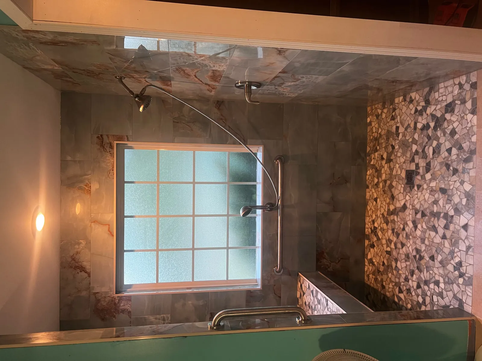 Onyx-look tile shower with a natural pebble mosaic accent wall and a glass-block window