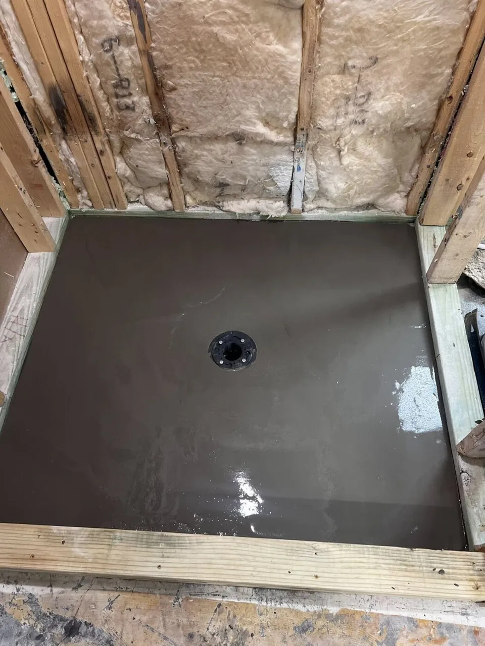 Freshly floated and sloped mortar shower pan around the drain before tiling
