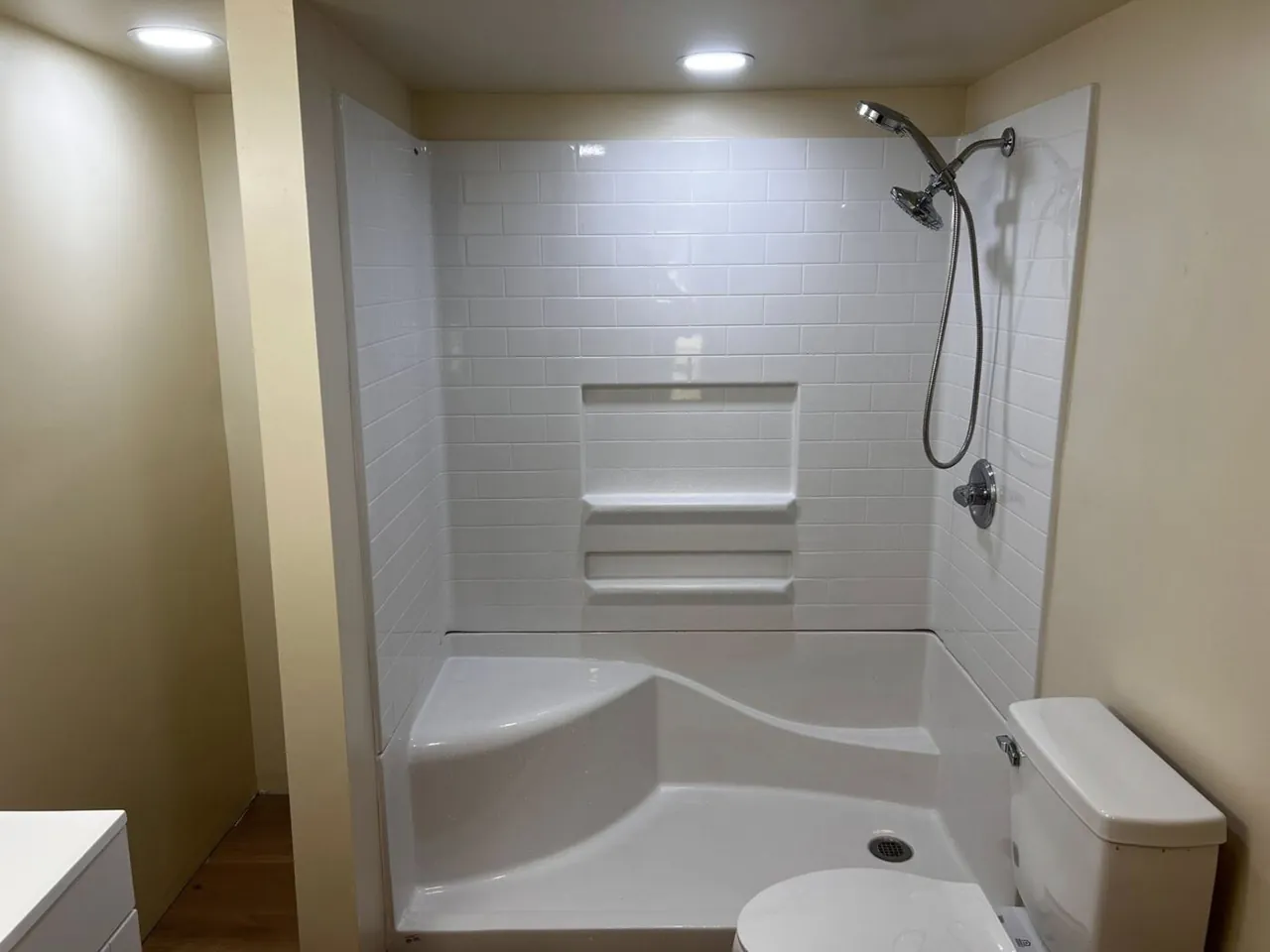 Refinished white tub-and-shower surround with subway tile pattern and shelves